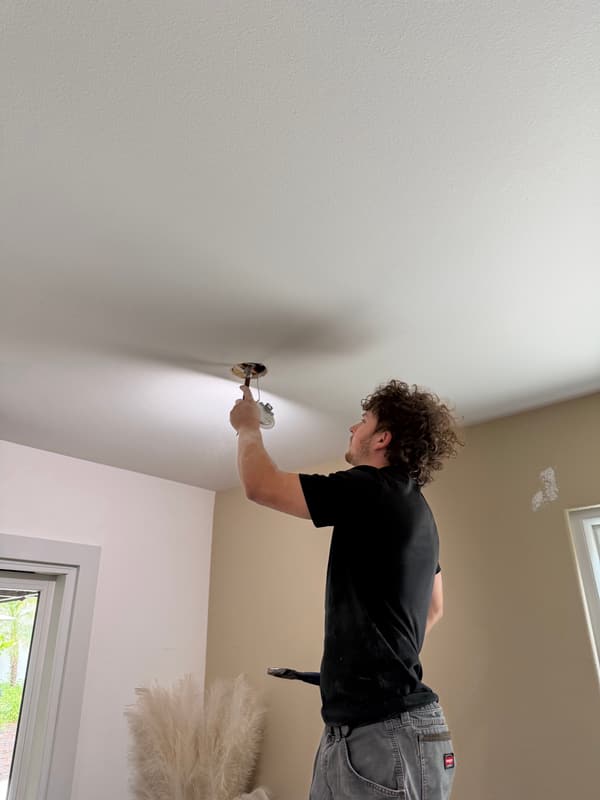 Installer connecting a ceiling light fixture in a bright room