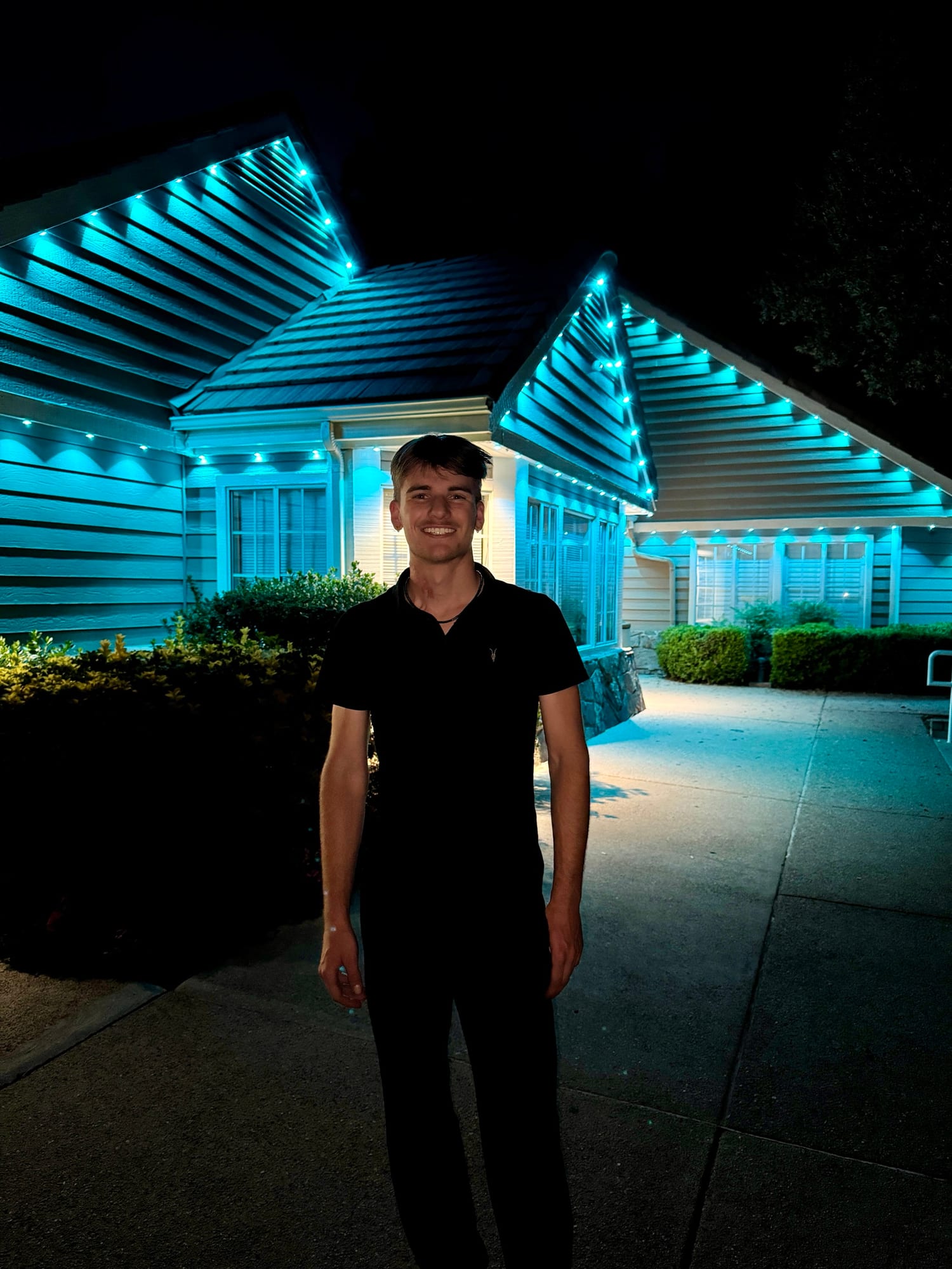 John Fox, owner of JFX Lighting, in front of a home lit in teal permanent lights