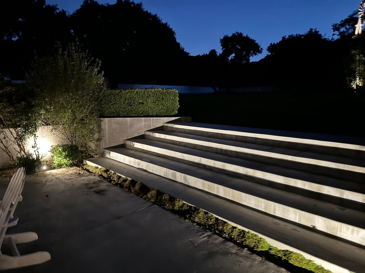 Wide outdoor steps and planting beds lit with low landscape lights at dusk