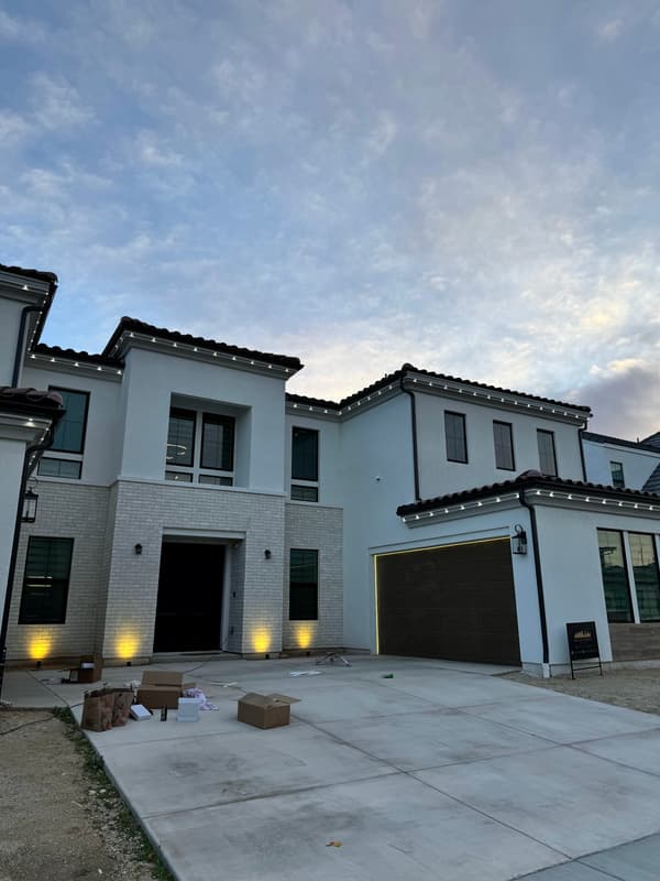 Modern two-story home with small uplights at the entry and garage