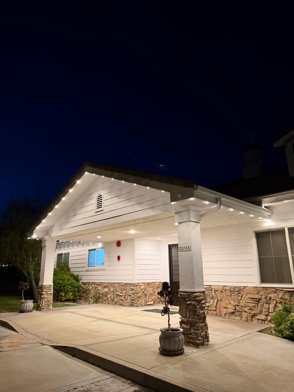 Single-story home at night with warm white lights along the roofline and porch