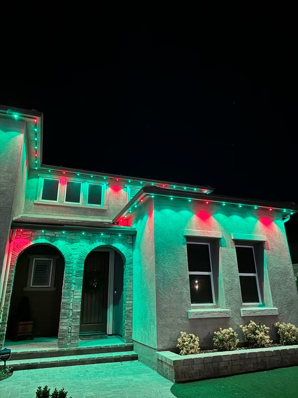Home with arched entries lit in red and green permanent eave lights for Christmas