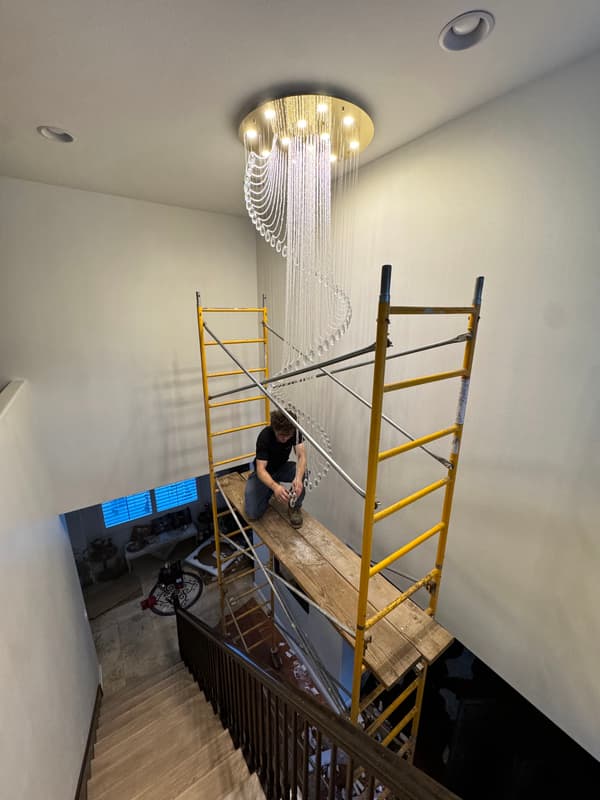 Crystal spiral chandelier being installed in a tall stairwell