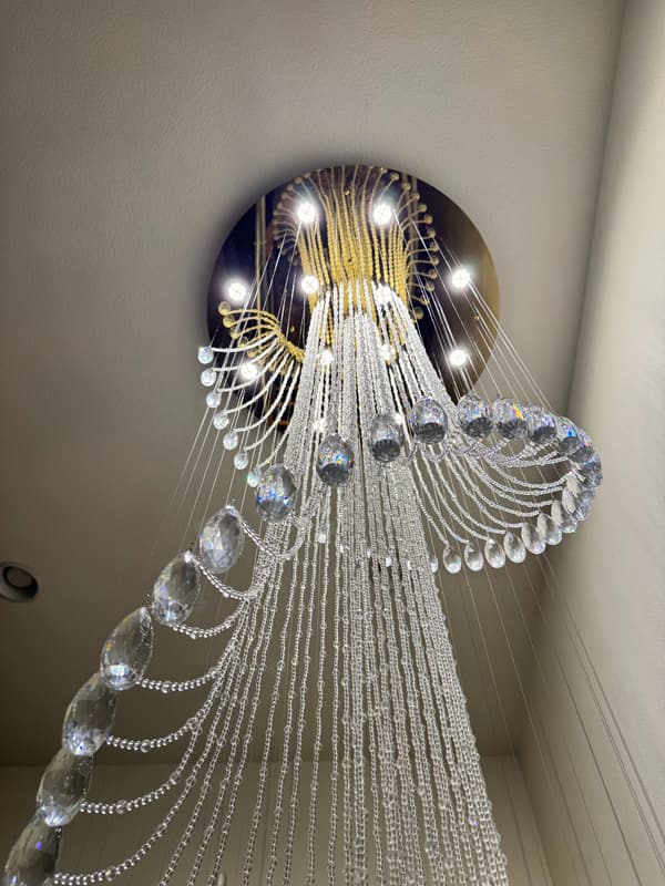 Tall crystal chandelier seen from below, hanging from a round lit canopy