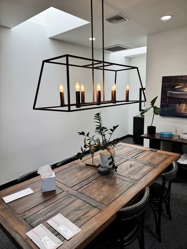 Black rectangular candle-style chandelier over a wooden dining table