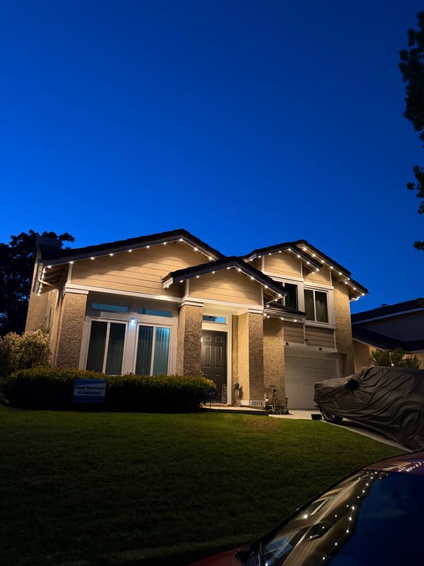 Two-story home at dusk with lights along the roofline