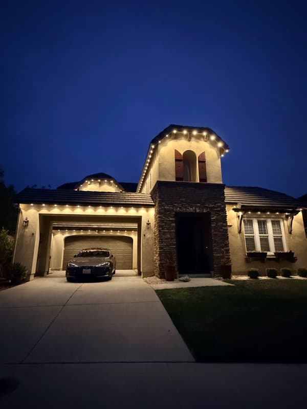 Single-story home at dusk with warm white lights along the roofline
