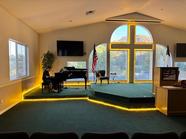 Stage with warm LED strip lights along its edges in a large carpeted room